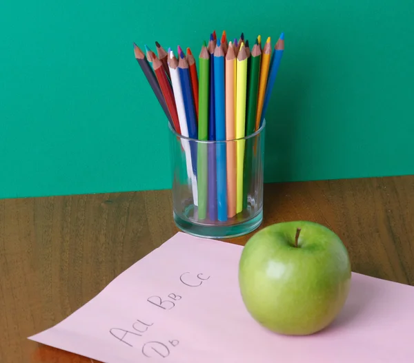 Bleistifte auf der Brille, grüner Apfel und Papier auf dem Schreibtisch. — Stockfoto