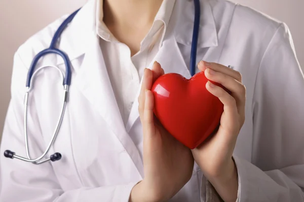 Kalbi steteskop tutan kadın doktor, beyaz arka planda izole edilmiş.