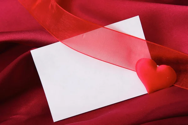 Tarjeta de invitación sobre fondo satinado de seda roja . —  Fotos de Stock