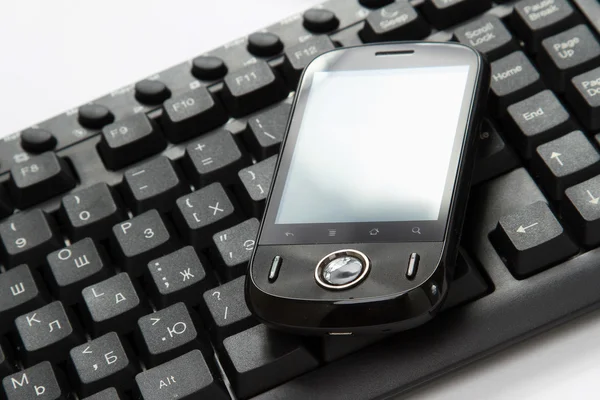 Business concept - a mobile phone over a keyboard — Stock Photo, Image