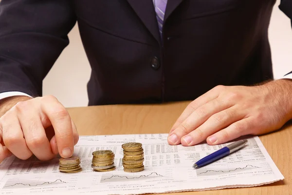 Hombre de negocios poniendo las monedas en columnas — Foto de Stock