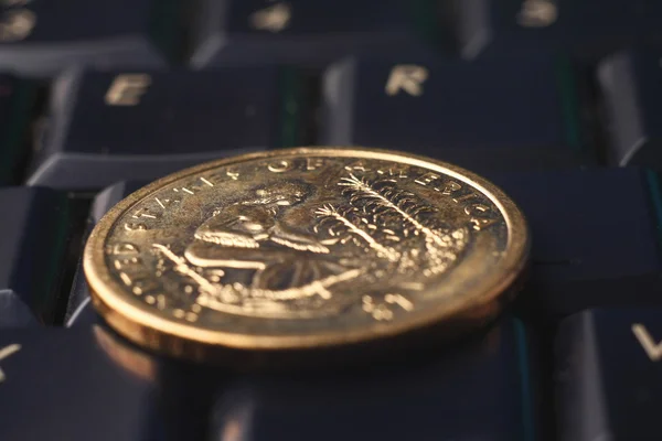 Una moneda de oro en el teclado — Foto de Stock