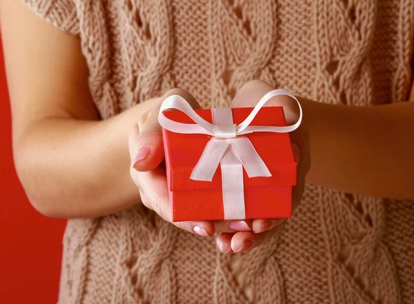 Female hand holding gift box isolated on red background — Stock Photo, Image