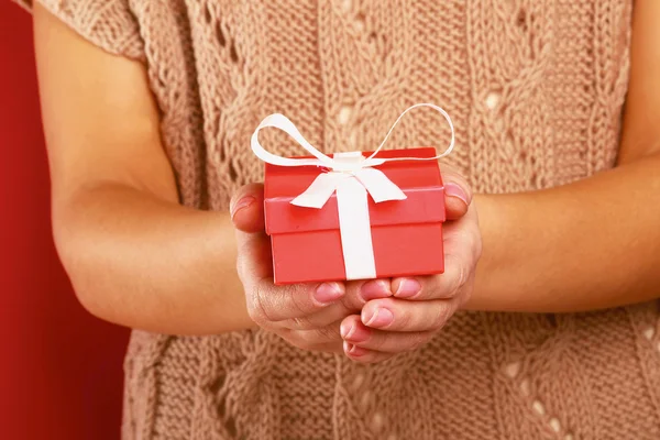 Female hand holding gift box isolated on red background — Stock Photo, Image