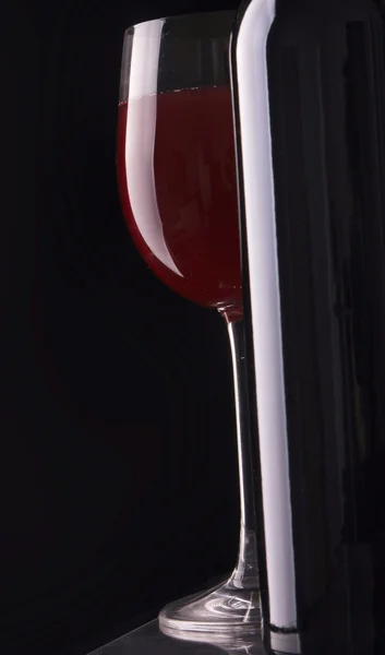 Elegant wine glass and a wine bottle in black background. — Stock Photo, Image