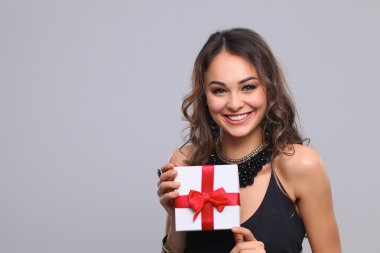 genç kadın mutlu gülümseme hediye kutusu gri arka plan üzerinde izole elinde tut