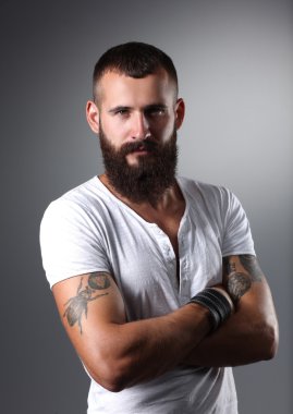 gri arka plan üzerinde izole çapraz kollu yakışıklı sakallı adam portresi