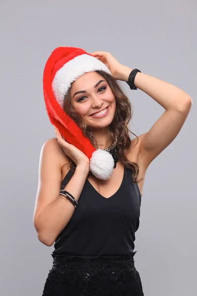 Atractiva mujer sonriente en Santa Cap. Aislado sobre un fondo gris . —  Fotos de Stock