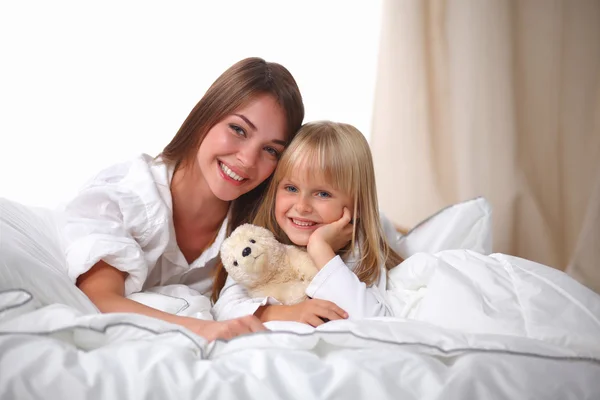 Woman and young girl lying in bed smiling — Stock Photo, Image