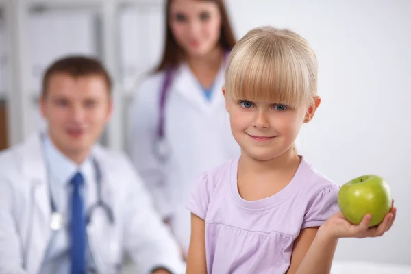 Kinder- und Medizinkonzept - Ärztin schenkt lächelndem kleinen Mädchen einen Apfel — Stockfoto