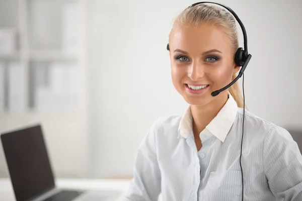 Retrato de una hermosa mujer de negocios trabajando en su escritorio con auriculares y laptop — Foto de Stock