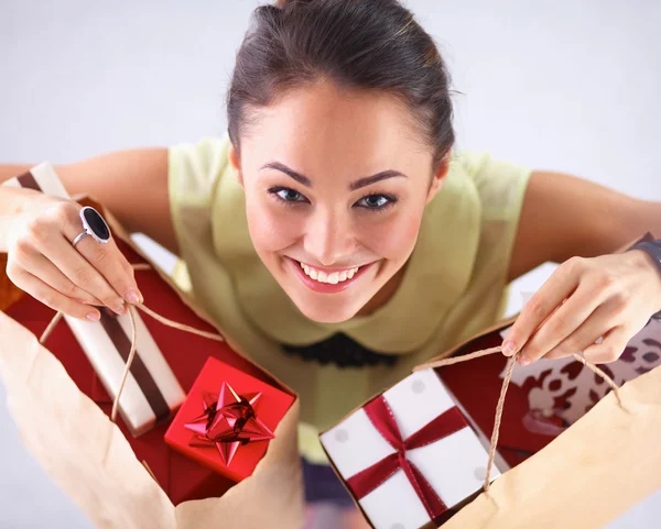 Donna sorridente con regali di Natale, isolata su sfondo rosso — Foto Stock