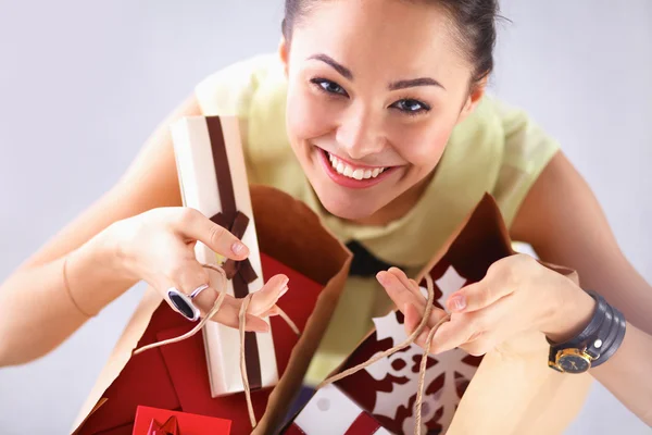 Uśmiechnięta kobieta z prezenty, na białym tle na czerwonym tle — Zdjęcie stockowe
