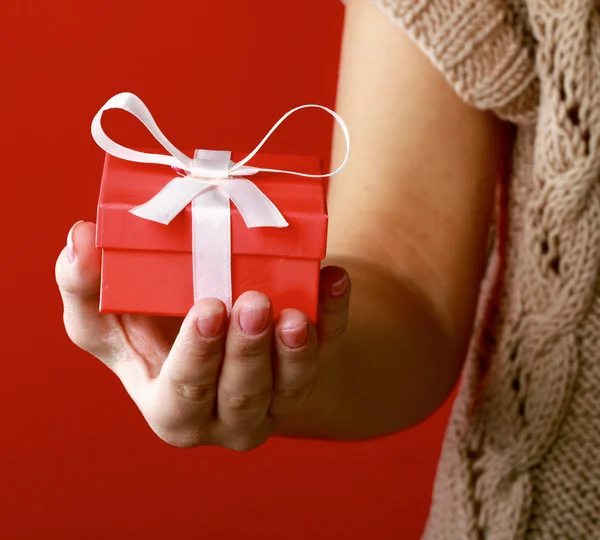 Feminino mão segurando caixa de presente isolado no vermelho — Fotografia de Stock