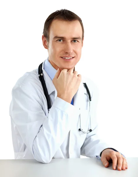 Portrét lékaře sedícího za stolem na bílém pozadí — Stock fotografie