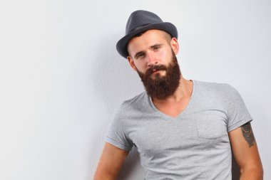 şapka ayakta, gri arka plan üzerinde izole yakışıklı sakallı adam portresi