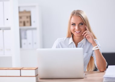 Ofiste dizüstü bilgisayarı olan çekici bir iş kadını.