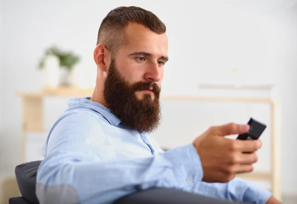Podnikatel sedí na pohovce v ve vestibulu s telefonem, izolovaných na bílém pozadí — Stock fotografie