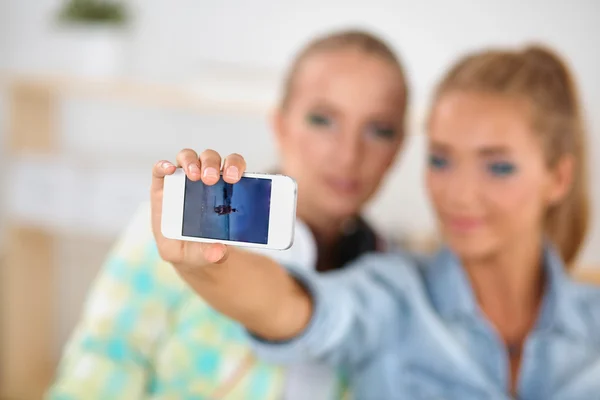 Dos chicas tomando fotos por teléfono en casa — Foto de Stock