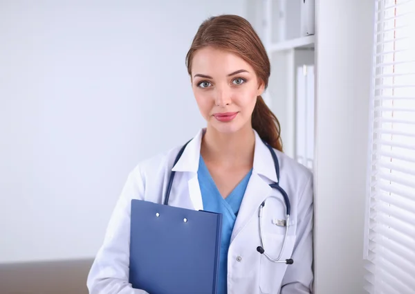 Smiling female doctor with a folder in uniform standing at hospital — Stock Photo, Image