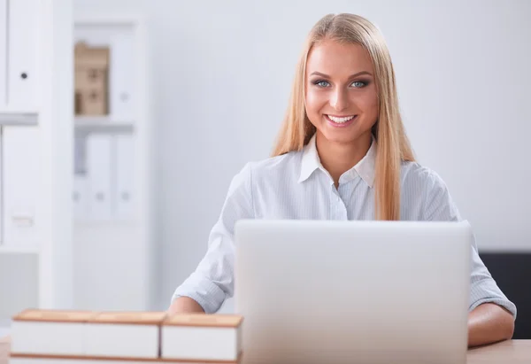 Привлекательная деловая женщина сидит на столе с ноутбуком в офисе — стоковое фото