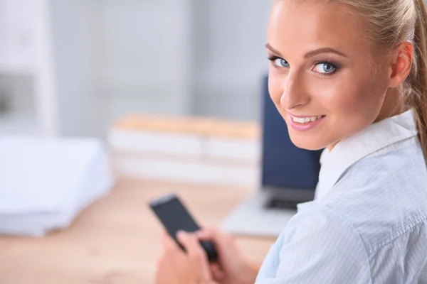 Empresária enviando mensagem com smartphone sentado no escritório — Fotografia de Stock