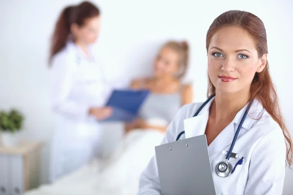 Médico sonriente con una carpeta en uniforme de pie en el hospital — Foto de Stock