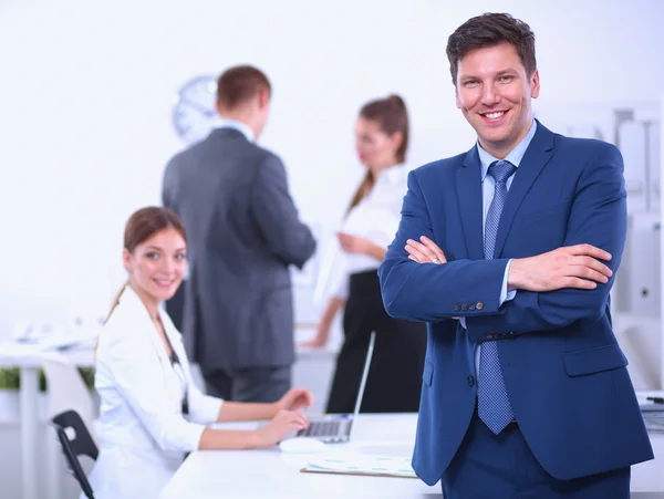 Uomo d'affari di successo in piedi con il suo personale in background in ufficio — Foto Stock