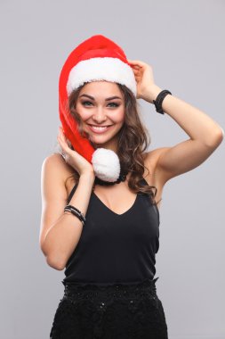 Noel Baba şapkalı çekici gülümseyen kadın. Gri bir arka plan üzerinde izole.