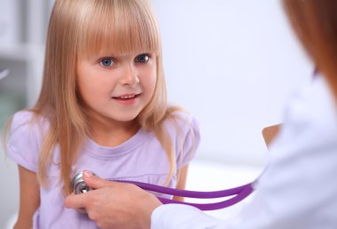 Kadın doktor ameliyatta steteskopla çocuğu muayene ediyor.