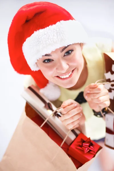 Chica feliz en el sombrero de santa celebración de una bolsa de compras con caja de regalo —  Fotos de Stock