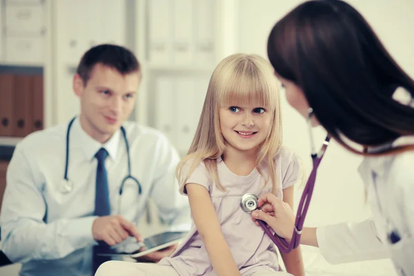 Female doctor examining child with stethoscope at surgery — Stock Photo, Image