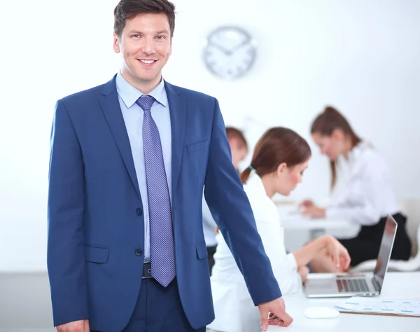 Erfolgreicher Geschäftsmann steht mit seinen Mitarbeitern im Hintergrund im Büro — Stockfoto