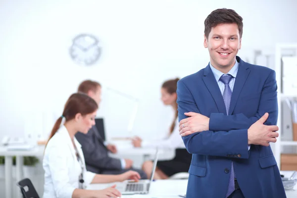 Erfolgreicher Geschäftsmann steht mit seinen Mitarbeitern im Hintergrund im Büro — Stockfoto