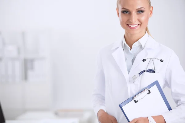 Médico sonriente con una carpeta en uniforme de pie en el hospital —  Fotos de Stock