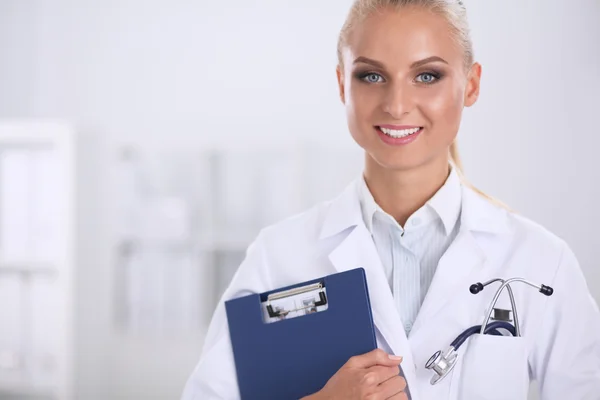 Lächelnde Ärztin mit Ordner in Uniform steht im Krankenhaus — Stockfoto