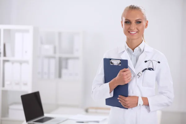 Lächelnde Ärztin mit Ordner in Uniform steht im Krankenhaus — Stockfoto