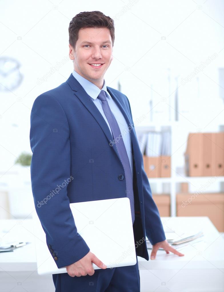 Business man or manager standing against his desk at the office