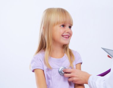 Kadın doktor ameliyatta steteskopla çocuğu muayene ediyor.