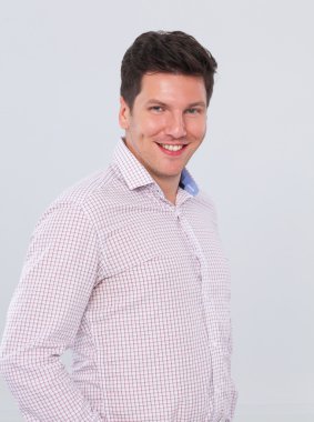 gri arka plan üzerinde duran, zeki genç bir adam portresi