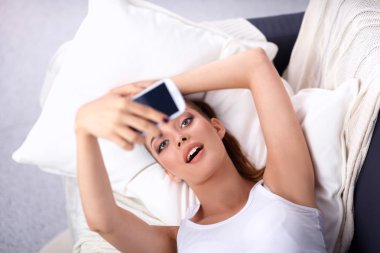 Yatak odasında cep telefonu ile kendini bir fotoğraf çekici mutlu esmer