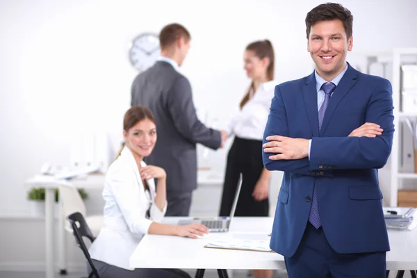 Successful business man standing with his staff in background at office — Stock Photo, Image