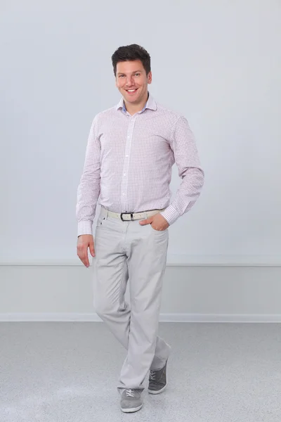 Portrait of a smart young man standing against gray background — Stock Photo, Image