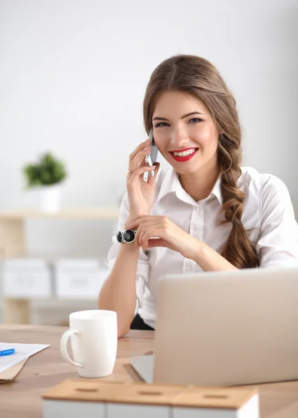 Jonge zakenvrouw zit aan het bureau en praat over de telefoon — Stockfoto