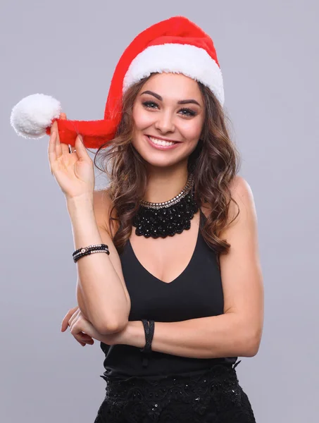 Aantrekkelijke lachende vrouw in Santa Cap. Geïsoleerd op een grijze achtergrond. — Stockfoto