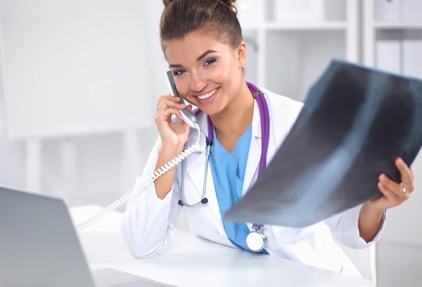 Femeie medic care caută scanare cu raze X și vorbește la telefon în centrul de diagnosticare, stând la birou — Fotografie, imagine de stoc