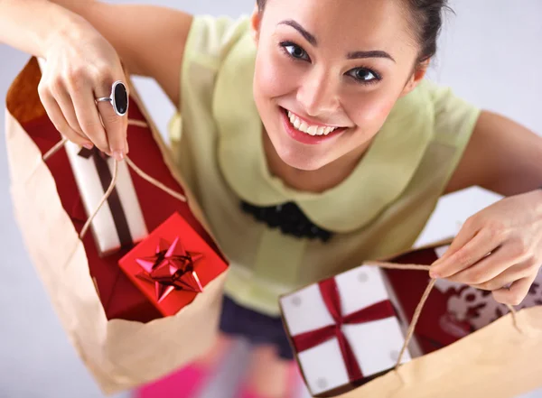 Улыбающаяся женщина с рождественскими подарками, изолированная на красном фоне — стоковое фото