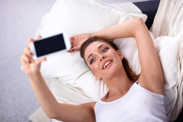 Morena feliz tomando una foto de sí misma con su teléfono móvil en el dormitorio — Foto de Stock