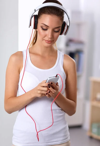 Mujer con auriculares escuchando música de pie en casa — Foto de Stock