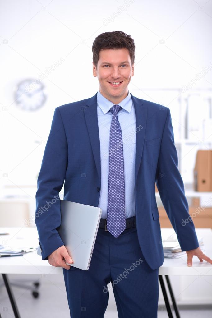 Business man or manager standing against his desk at the office